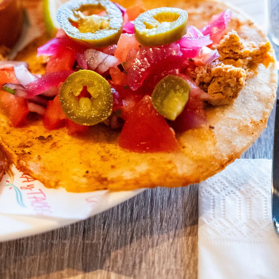 Soft taco met pulled chicken, pico de gallo, ingelegde rode ui en jalapeno